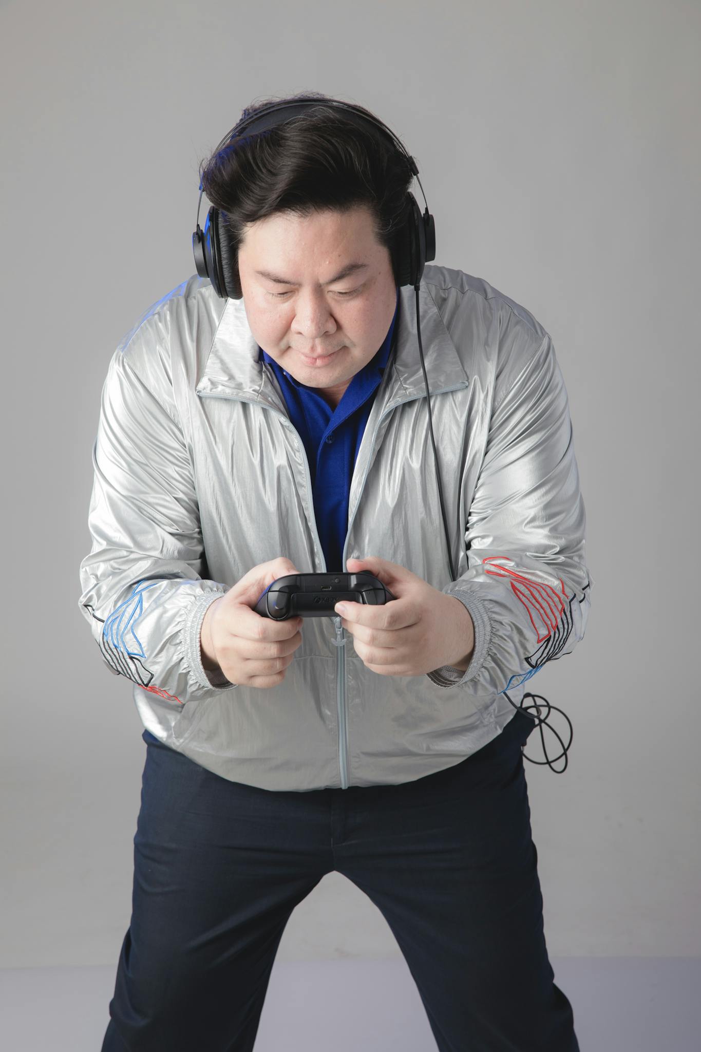 Man in silver jacket and headphones intensely playing a video game.